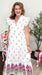 Woman wearing a white dress with floral patterns indoors.